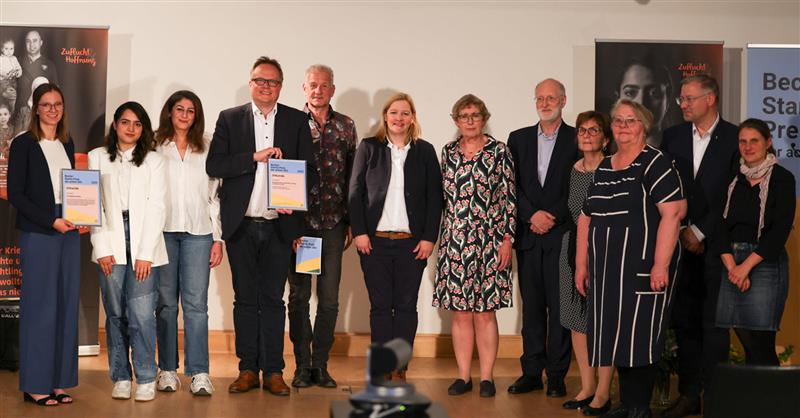 Auf dem großen Abschlussbild (v.l.n.r.): Preisträgerin Dr. Magdalena Hürten; vom Projekt Kirchenasyl St. Sixtus in Haltern am See:  Razeya Rosooli, Ruken Ossi, Michael Ostholthoff, Markus Wenzel, Christiane Pinger; Laudatorin Sigrid Düringer; Mitglieder der Vergabekommission: Matthias Copray, Helga Engler-Heidle, Pia Arnold-Rammé, Prof. Dr. Wolfgang Beck, Eva-Maria Reinwald.